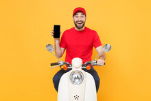Delivery Man In Red Cap T-shirt Uniform Driving Moped Motorbike Scooter Hold Mobile Phone Isolated On Yellow Background Studio Guy Employee Working Courier Service Quarantine Pandemic Covid-19 Concept