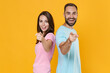 © ViDi Studio - Side view of cheerful couple friends guy girl in blue pink t-shirts isolated on yellow background. People lifestyle concept. Mock up copy space. Standing back to back pointing index fingers on camera.