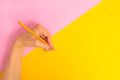 The left hand is holding a pencil and is about to write something on a bright pink-yellow background. International Left-handers Day on August 13.