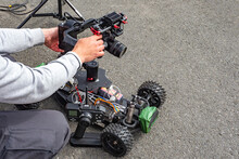 Man Mounts A Camera To A Radio-controlled Model Of A Car. Man Sets A Photo Camera. Camera On The Radio-controlled Car. Man Sets Up Photo Equipment. Concept - Professional Filming Equipment.