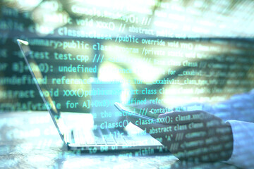 Hand using laptop and abstract coding text interface on screen.