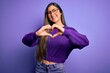 © Krakenimages.com - Young beautiful smart woman wearing glasses over purple isolated background smiling in love doing heart symbol shape with hands. Romantic concept.
