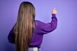 © Krakenimages.com - Young beautiful smart woman wearing glasses over purple isolated background Posing backwards pointing ahead with finger hand
