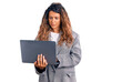 © Krakenimages.com - Young hispanic woman with tattoo holding laptop thinking attitude and sober expression looking self confident