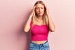 © Krakenimages.com - Young blonde woman wearing casual clothes with hand on head, headache because stress. suffering migraine.