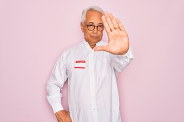 Middle age senior grey-haired man wearing hello my name is introduction sticker with open hand doing stop sign with serious and confident expression, defense gesture