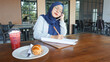 © BAGUS SATRIYA - asian business girl is taking notes and is on the phone