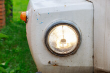 Close Up Of The Headlight Of An Old Abandoned Truck With Rusted White Panels