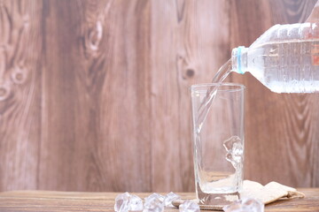 Poster - Pouring drinking water in glasses on wood table background and space for text