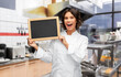 © Syda Productions - cooking, advertisement and people concept - happy smiling female chef holding black chalkboard over restaurant or kebab shop kitchen background