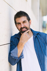 Cheerful bearded man with hand on chin while looking camera