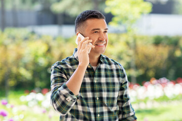 Wall Mural - gardening, communication and people concept - happy smiling middle-aged man calling on smartphone at summer garden