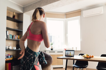 young woman dancing at home following video lesson on the laptop. pretty female repeating exercises 