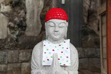 Canvas Print - Front view of a stone buddha statue decorated with clothes