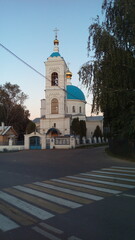 Wall Mural - A modest white stone Church with blue domes and a straight bell tower on the opposite side of the road