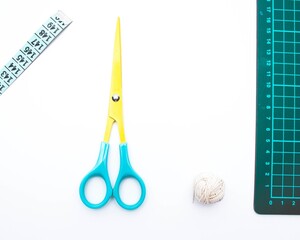 Wall Mural - Overhead shot of a scissors, yarn, cutting mat and measuring tape on a white surface