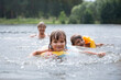 canvas print picture - Happy kids  swimming in the lake on hot summer day. Kids learn to swim and having fun with grandparents. Staycations, hyper-local travel,  family outing, getaway, natural environment