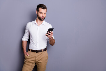 Canvas Print - Portrait of confident smm worker man agent use cellphone read social network colleagues news wear white shirt trousers isolated over gray color background