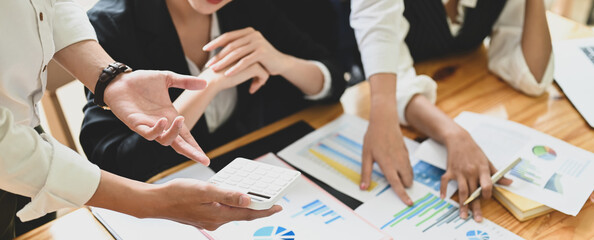 Business people are meeting together at the wooden working desk surrounded by paperwork.