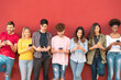 © Alessandro Biascioli - Group young friends using mobile smartphone outdoor - Millennial generation having fun with new trends social media apps - Youth technology people addicted - Red background