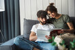 © Drobot Dean - Lovely young couple relaxing on a couch at home, reading magazine
