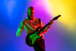 © master1305 - Tensioned. Young caucasian inspired and expressive musician, guitarist performing on multicolored background in neon. Concept of music, hobby, festival, art. Joyful artist, colorful, bright portrait.