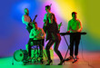Motion. Young caucasian inspired and expressive musicians, band performing on multicolored background in neon. Concept of music, hobby, festival, art. Joyful artist, colorful, bright portrait.