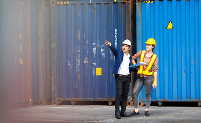  Man manager and woman Supervisor dock cargo checking and control loading Containers box at container yard port of import and export goods. Unity and teamwork concept