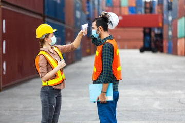 Temperature measurement with employee temperature meter before entering work at container yard. People working on the import and export concept. Professional engineering team.