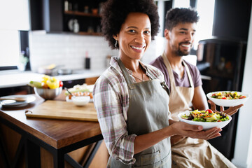 Wall Mural - Beautiful young couple cooking healthy food together at home. Having fun in the kitchen.