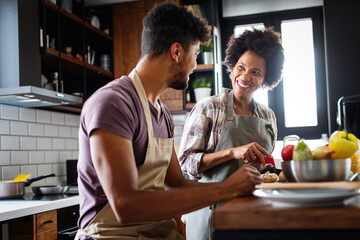 Wall Mural - Happy young couple cooking together in the kitchen at home.