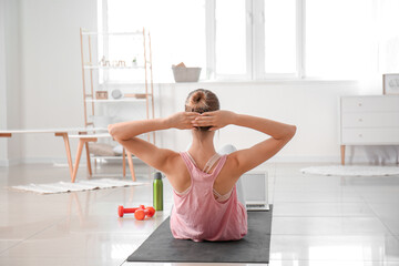 Sporty young woman with laptop training at home