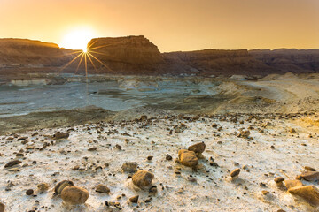 Sun bursts as it sets behind Masada, ancient Jewish fortress in the Judean desert - location of Herod's palaces and of the Roman siege, now one of Israel's most popular tourist attractions; Dead Sea