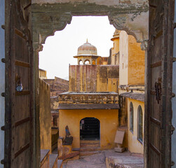 Breathtaking architecture details and panoramic scenic building view of Amber Fort and Palace during morning hours in yellow and orange light near Jaipur in Rajasthan in India with historic walls