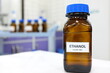 Selective focus of ethanol or ethyl alcohol brown amber glass bottle inside a laboratory. Blurred background with copy space.