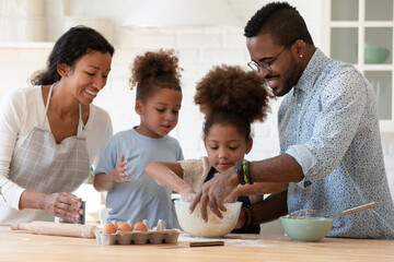 Overjoyed young african american family with little kids prepare dough baking pie or cookies in kitchen together, happy biracial parents cooking with small children, make sweet breakfast pastry