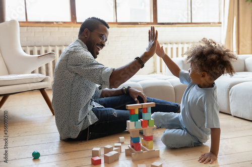 Cuadros en Lienzo Happy young african American father and little ethnic son give high five playing
