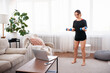 © Admiral - Sporty woman doing biceps exercise with dumbbells and watching online workout session on laptop, training in living room
