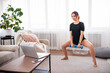 © Admiral - Online workout at home. Smile woman exercising with dumbbells in living room and watching fitness class on laptop. Copy space