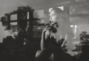 Alone, a beautiful woman sat and looked out at the window at night, black and white picture