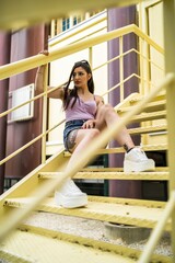 Poster - Rebellious caucasian female with tattoos and in jeans skirt posing while sitting on the stairs