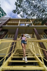 Wall Mural - A young caucasian female posing while standing on the yellow stairs of a building