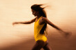 © Cavan Images - Artistic speed blur of young woman running against yellow wall