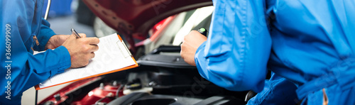 Fotografía Banner of automotive mechanic men with assistant checking damage under-car condition, vehicle maintenance technician write on checklist document in garage at auto repair shop