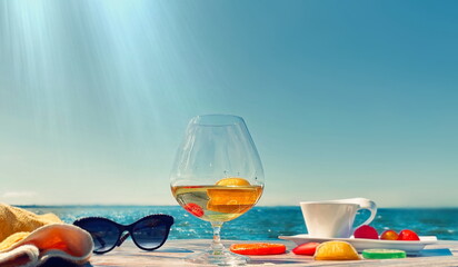   summer beach restaurant glass of juice sunglasses and cup of coffee with exotic fruits  on table top ,horizon sea and  blue sky  at bright  day background  vacation  leisure 