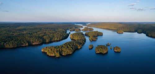 Wall Mural - Aerial panorama of beautiful blue lake, islands and green summer forest in Finland. Blue sky. Top view. Summer sunset lanscape.