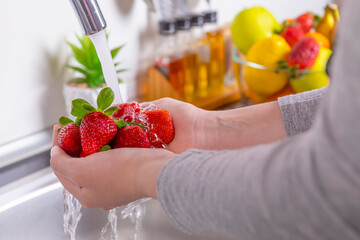 Woman washing strawberries in the kitchen