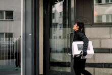 Young Delivery Woman Delivering Package At Building
