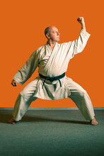 A Karate Man In A White Kimono With A Black Belt Does Kata Exercises.