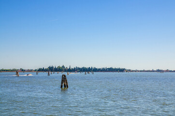 Wall Mural - Panoramic view of San Francesco del Deserto island in Venetian Lagoon water with wooden poles. View from Burano island. Venice Province, Veneto Region, Northern Italy